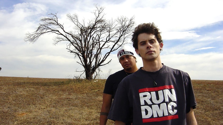 Hau and Daniel of Koolism stand in a big, open field in front of a large tree with no leaves