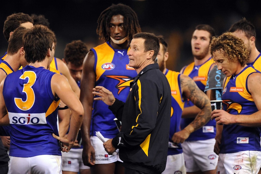 West Coast Eagles coach John Worsfold speaks to his team on the field during a break in play.