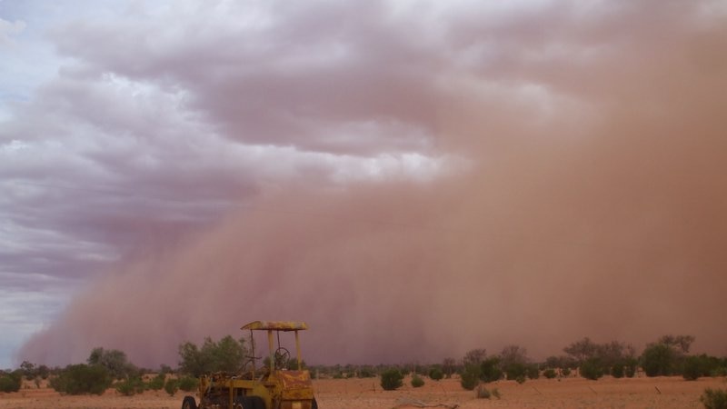 dust storm over desert landscape with tractor