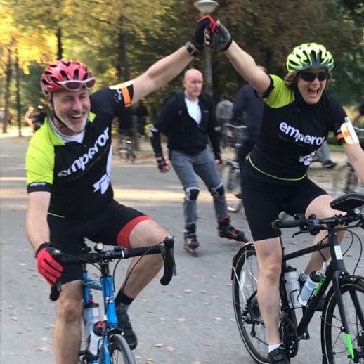 A woman on a bike holding her hands up in victory