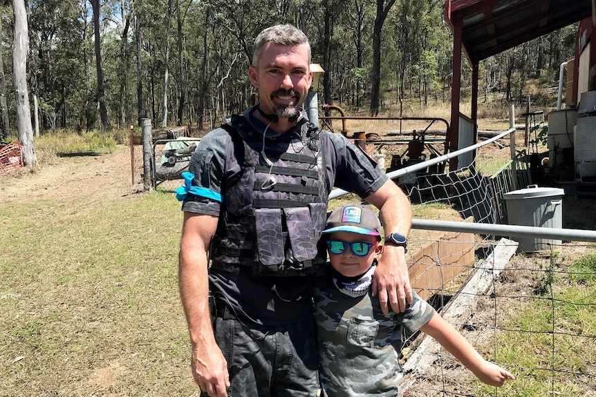 Gel ball game organiser Brent Alderton, stands with a young boy, both dressed in camouflage clothes in bush at Pimpama.