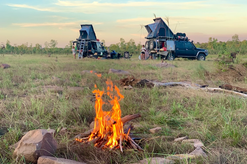 A campfire burns close to where two four-wheel-drive campers are parked