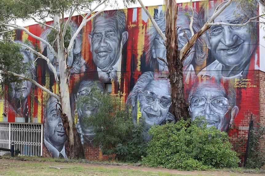 Murals of legendary Aboriginal activists are set against the red, black and yellow of the Aboriginal flag on a wall.