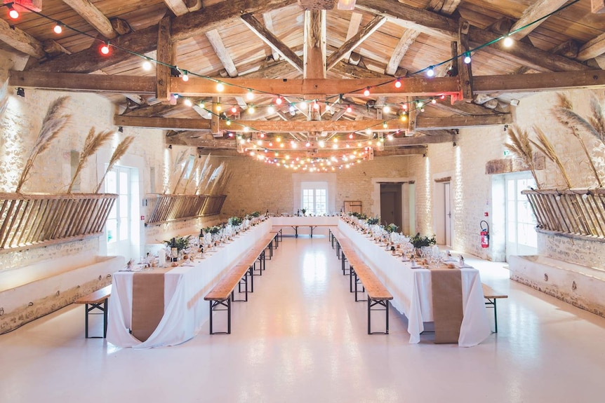 A beautifully decorated hall with three long tables ready for a wedding reception.