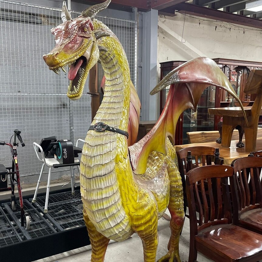 a large yellow dragon sculpture standing in a room full of furniture ready for auction