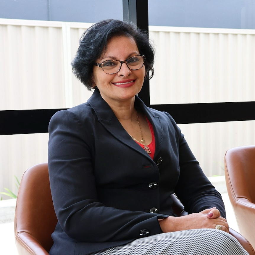 A professional portrait of Talat Uppal sitting and smiling at the camera.