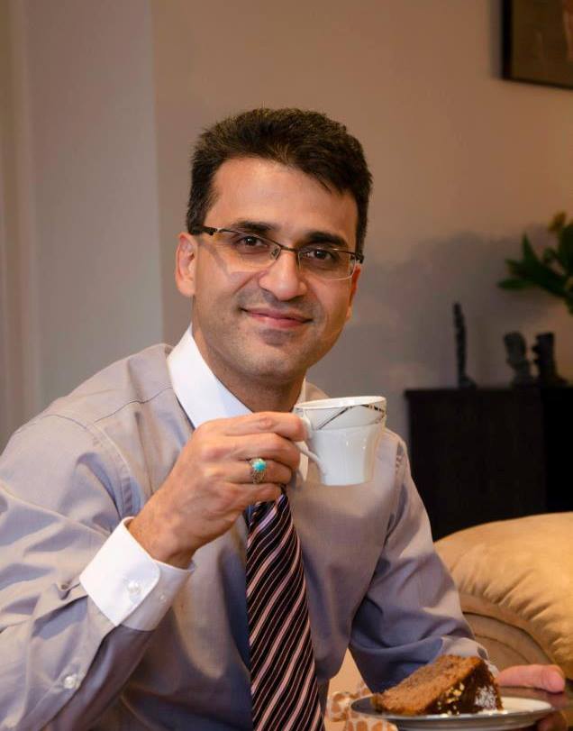 Seyyed Abdolzadeh Ali Farshchi dressed in shirt and tie  with a cup of tea and cake