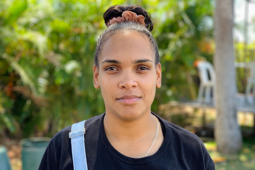 A woman in a black tshort looks at the camera pensively