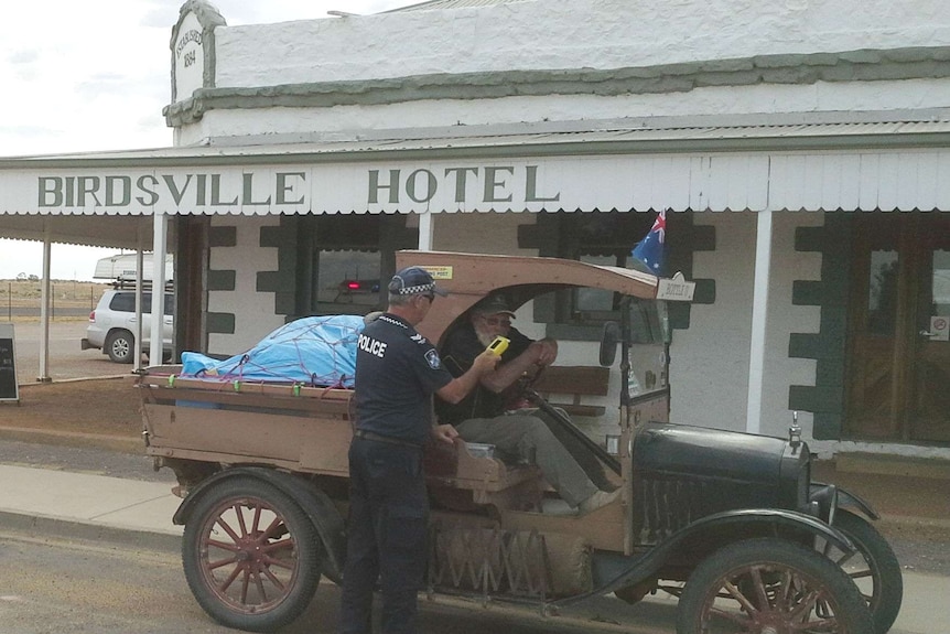 The driver of a vintage car being breath tested by police outside the Birdsville Hotel