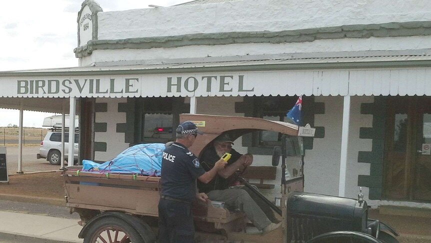 The driver of a vintage car being breath tested by police outside the Birdsville Hotel