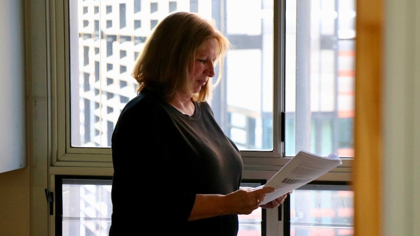 Professor Sandra van der Laan reads a document in front of a window.