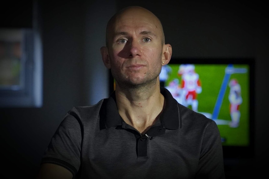 A portrait of a man in front of a sports game.