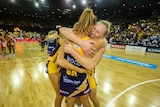 Three lighting players celebrate their win in the Netball Grand Final hugging just after the match has finished