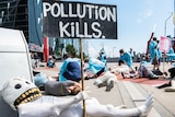 protestors dressed as health workers, prominent sign says "pollution kills"