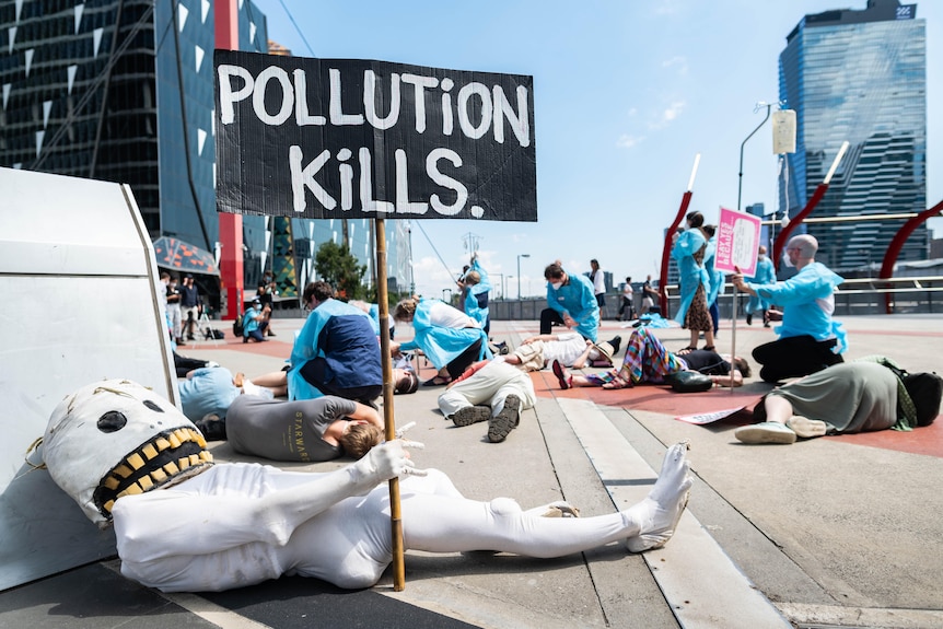 protestors dressed as health workers, prominent sign says "pollution kills"