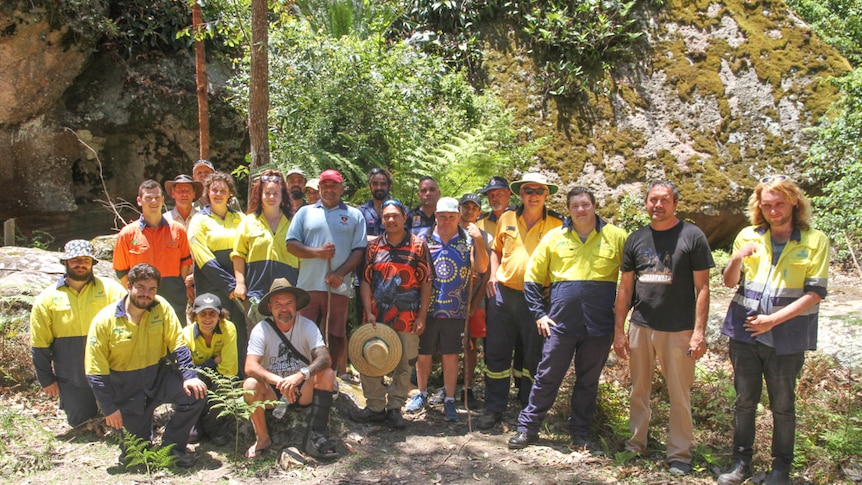 A group of 20 people gather in the bush together for a photo shoot