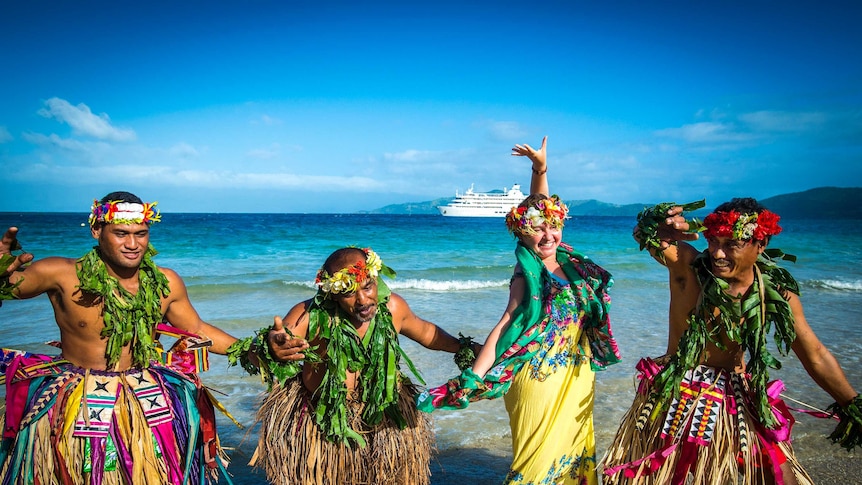 A group dancing on the beach in traditional dress.