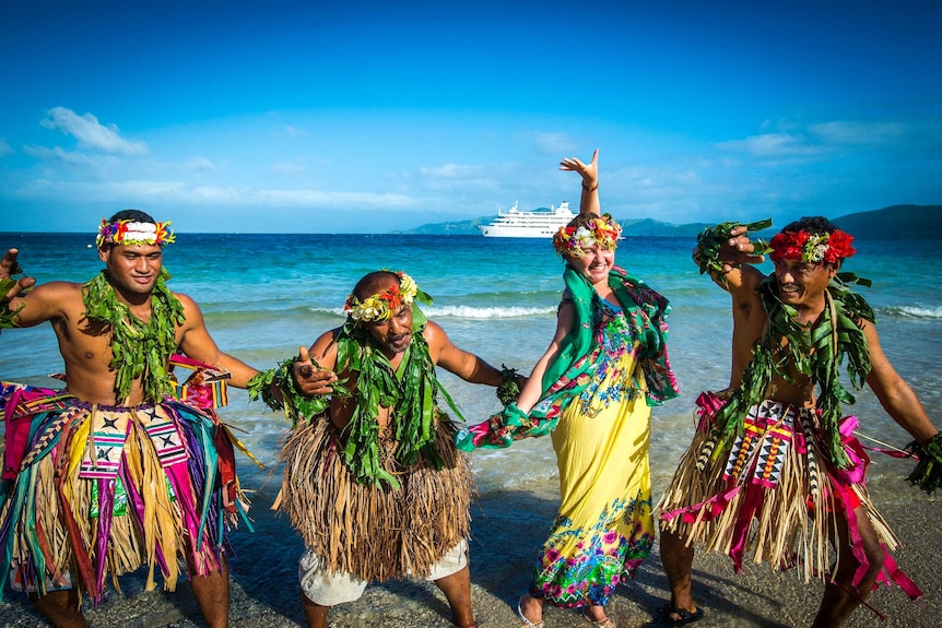 A group dancing on the beach in traditional dress.