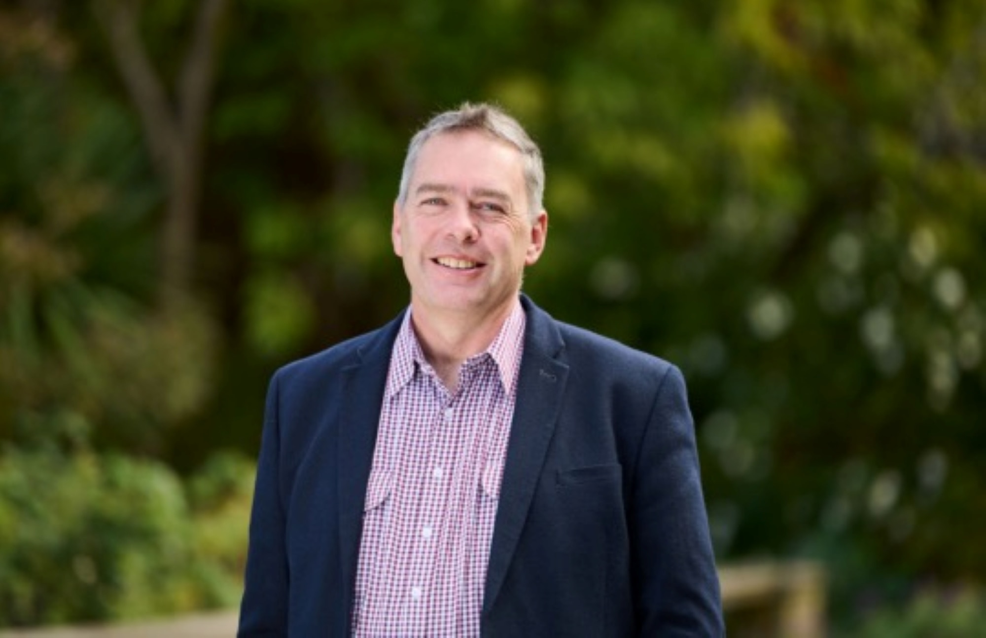 Justin Buckley wears a suit and smiles at the camera.