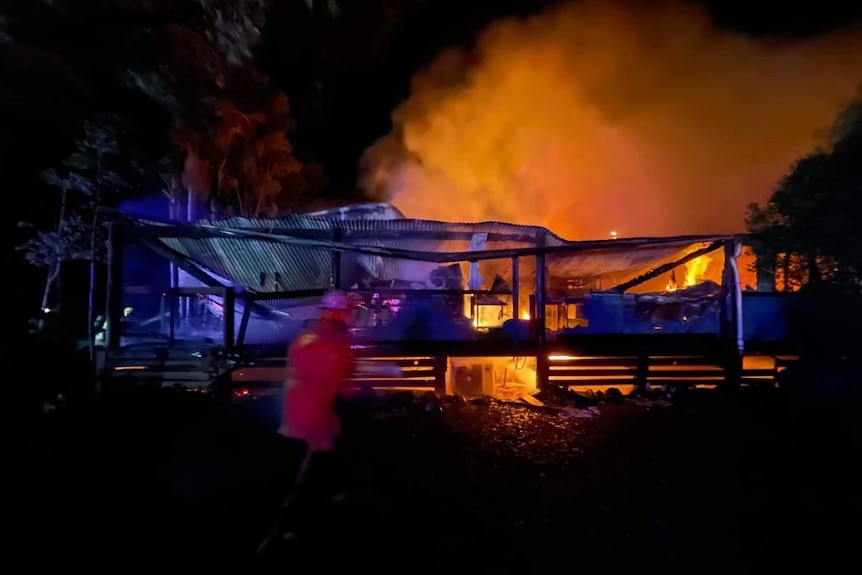 A large building burning with steel roof collapsed and flame sout the back