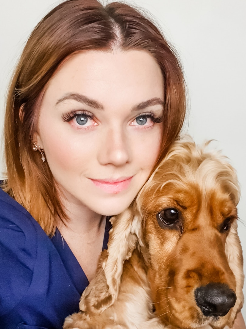 A young woman in scrubs with a cute cocker spaniel. 