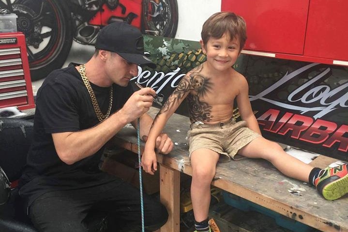 Benjamin Lloyd airbrushes a sleave tattoo on a child.
