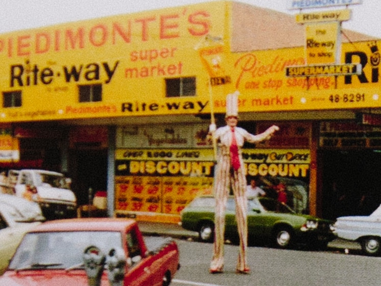 An image of the front of Piedimonte's Supermarket in the 1970s with a man on stilts in a tall top hat.