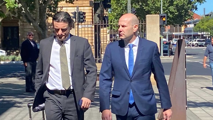Two men wearing suits walking on a city street