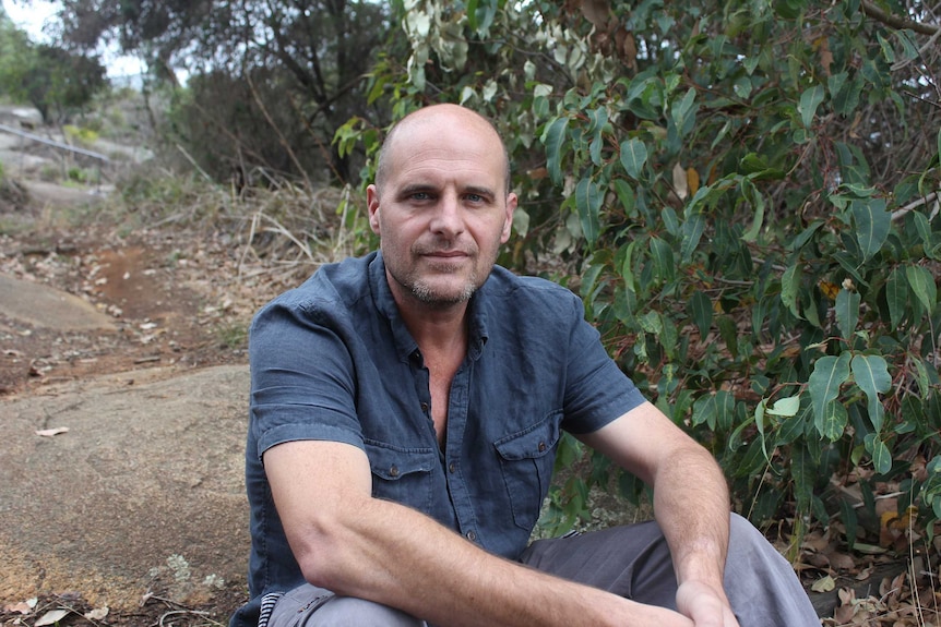 Shaun Ossinger sits on a rock in Albany