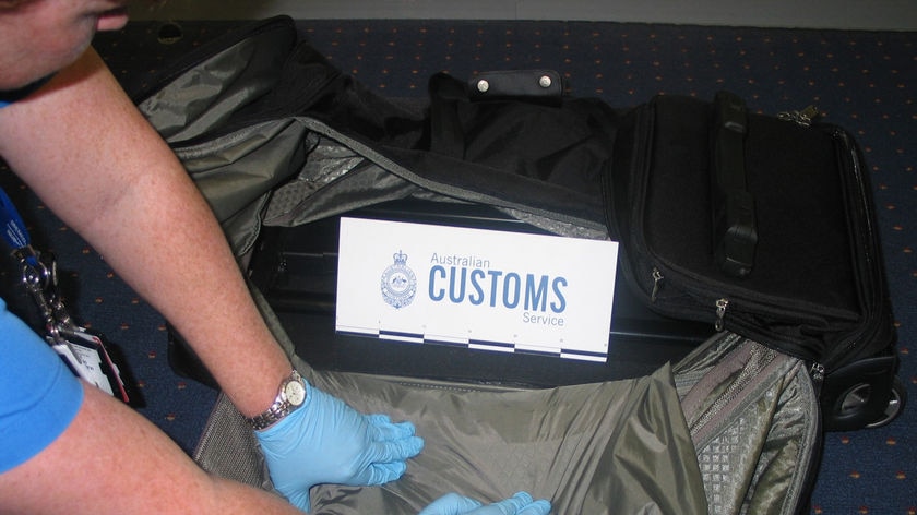 Customs officials at Sydney airport inspect a sports bag