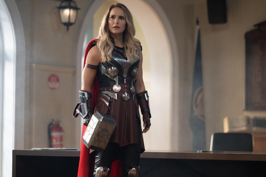 Natalie Portman in costume as Mighty Thor holding the character's hammer