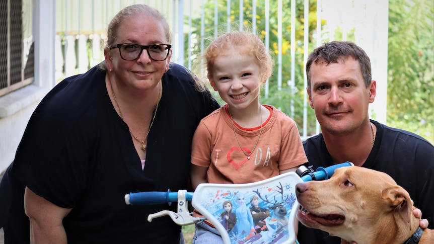 A oortrait of a husband and wife, their daughter and dog at their home in Darwin.