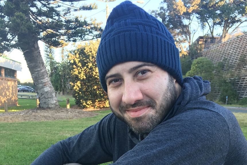 Double-lung transplant patient Jordan Trieger smiles as he sits in a park.