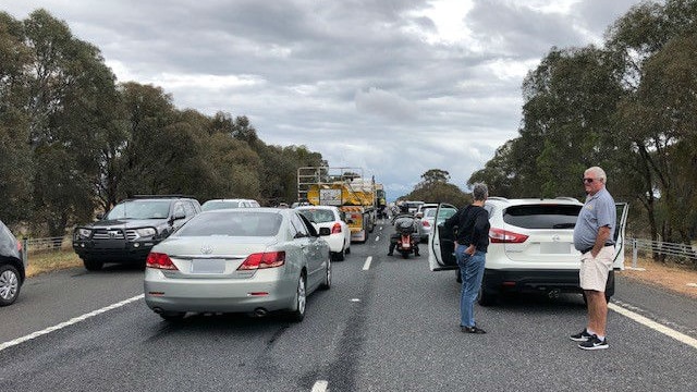 People stand on the Hume Freeway as traffic is backed up.