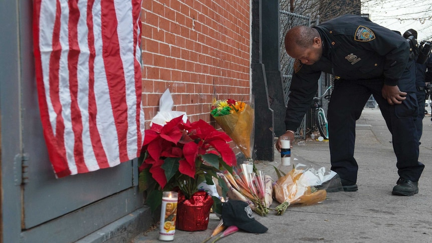 A police officer lays flowers at a makeshift memorial for two police officers shot dead in New York City