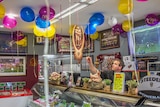 Owner Matt Roberts puts up decorations in the butcher shop ahead of the grand final.