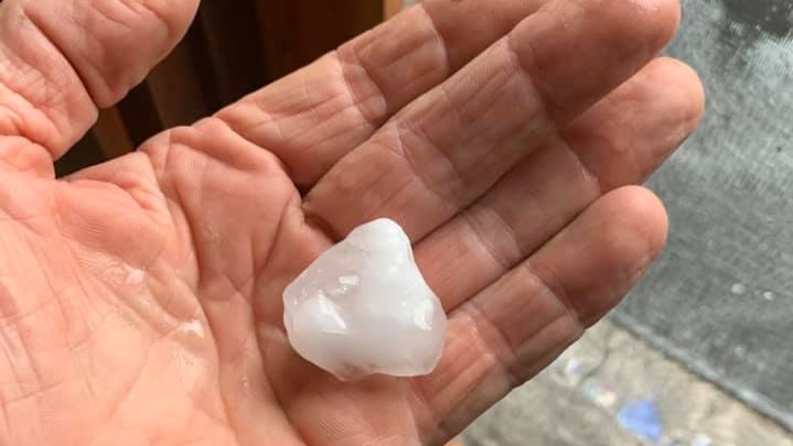 A piece of hail in the palm of a hand.