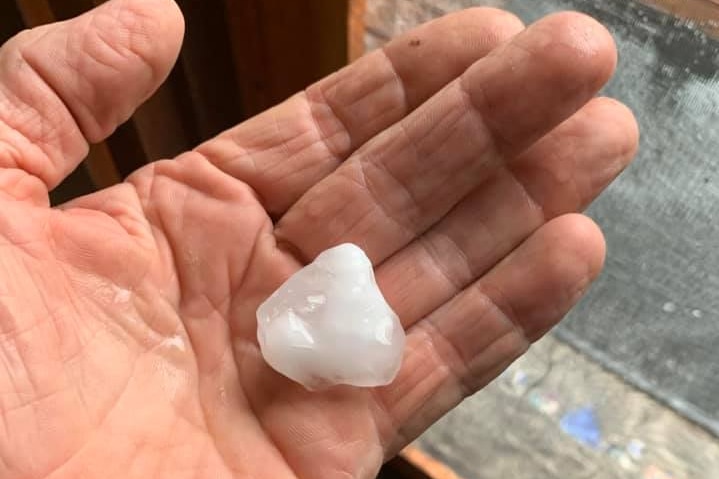 A piece of hail in the palm of a hand.