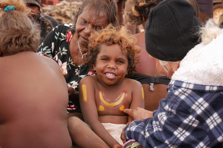 A Balgo child being painted by elders, August 2022. 