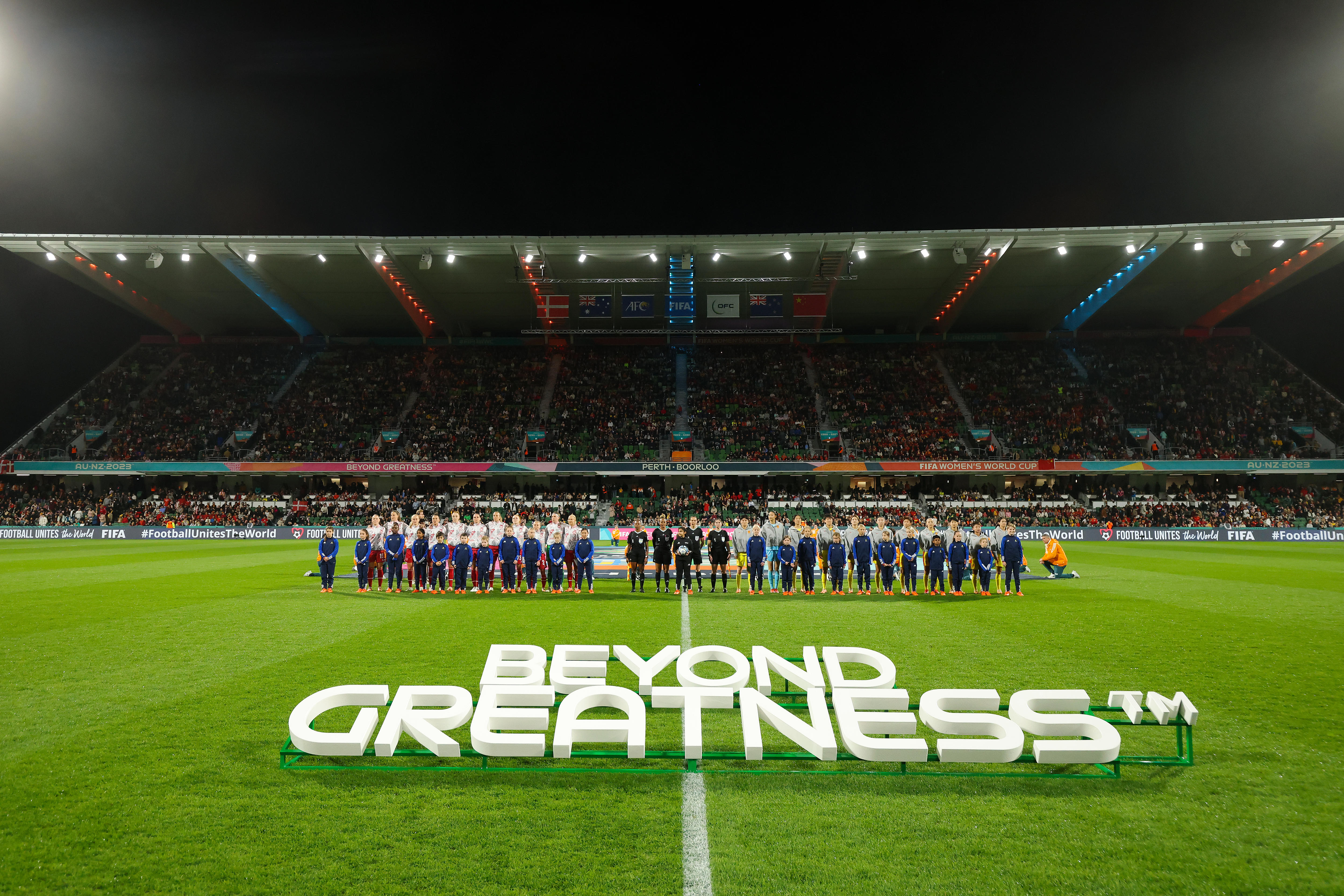 A soccer team stands in the middle of an oval