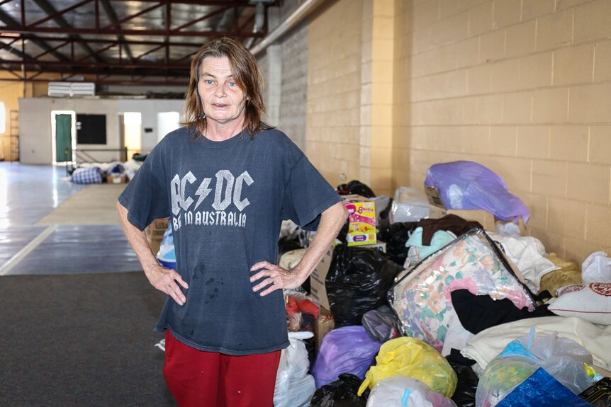 Karina Bale stands next to a pile of donated clothes and household items