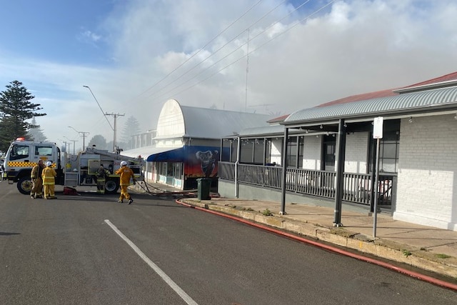 A building with smoke and firefighters out the front. 