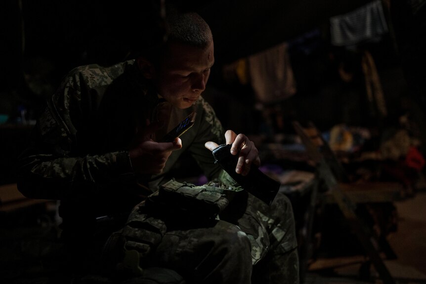 A Ukrainian Border Guard soldier cleans the magazine of his weapon in a dark room
