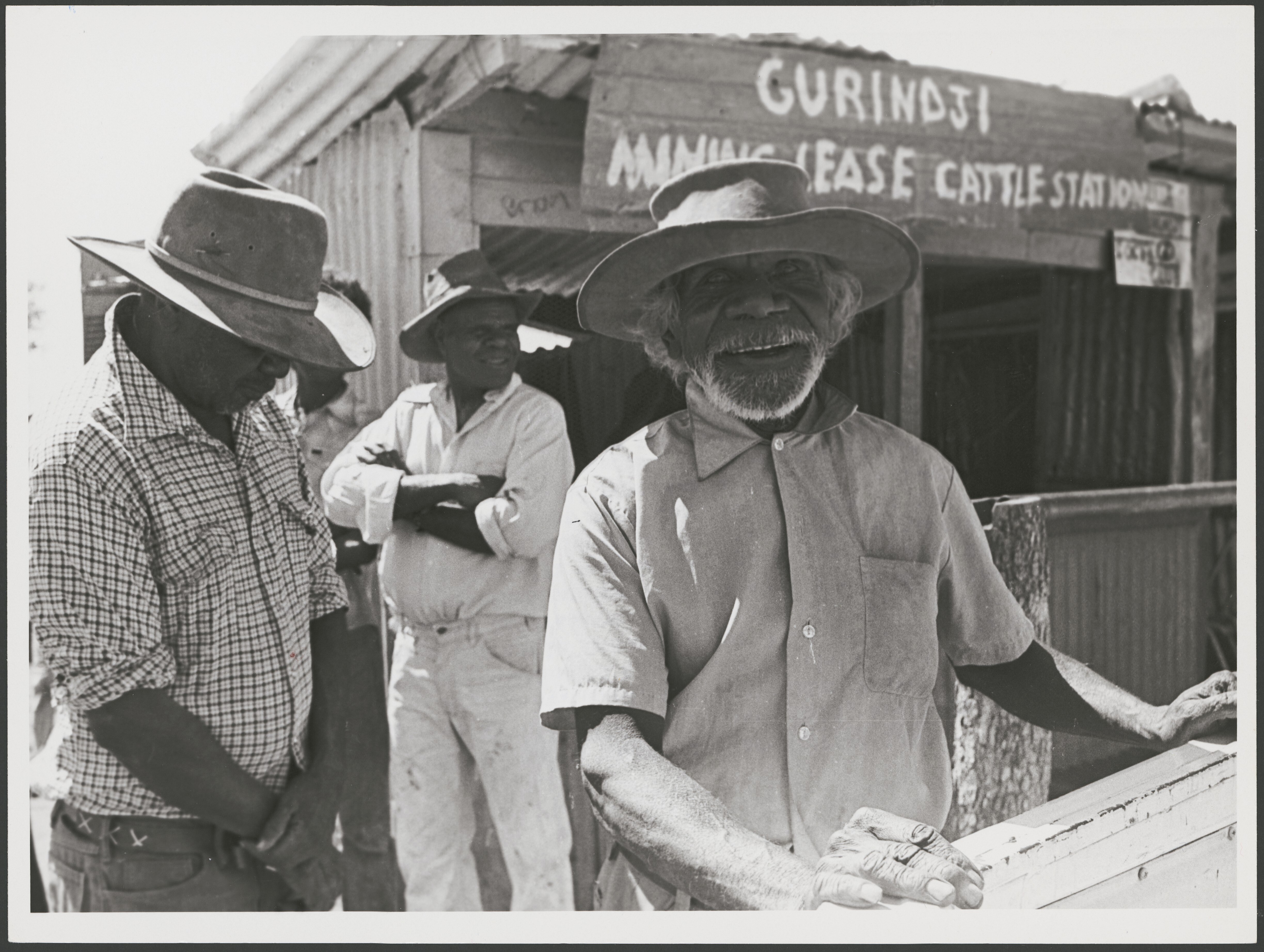 Black and white photo of 3 Aboriginal stockmen, one smiling at camera, all in wide-brim hats.