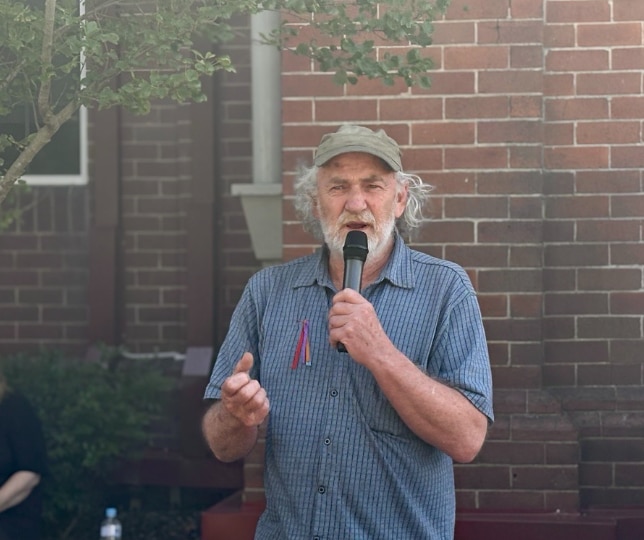 Un hombre con barba sostiene un micrófono.
