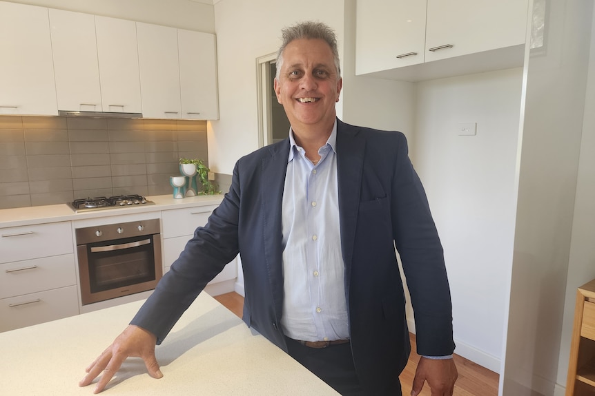 Peter Schenck director Ray White Blackburn in Melbourne sells a home in the eat of Melbourne. Stands in kitchen smiling. 