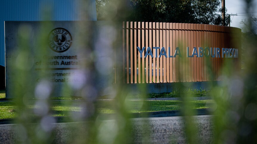 A sign reading Yatala Labour Prison behind blurred greenery 