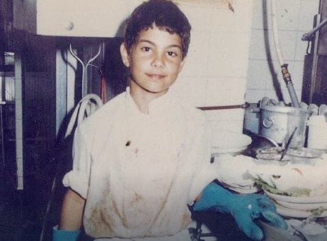 Una foto antigua de un niño pequeño en la cocina.