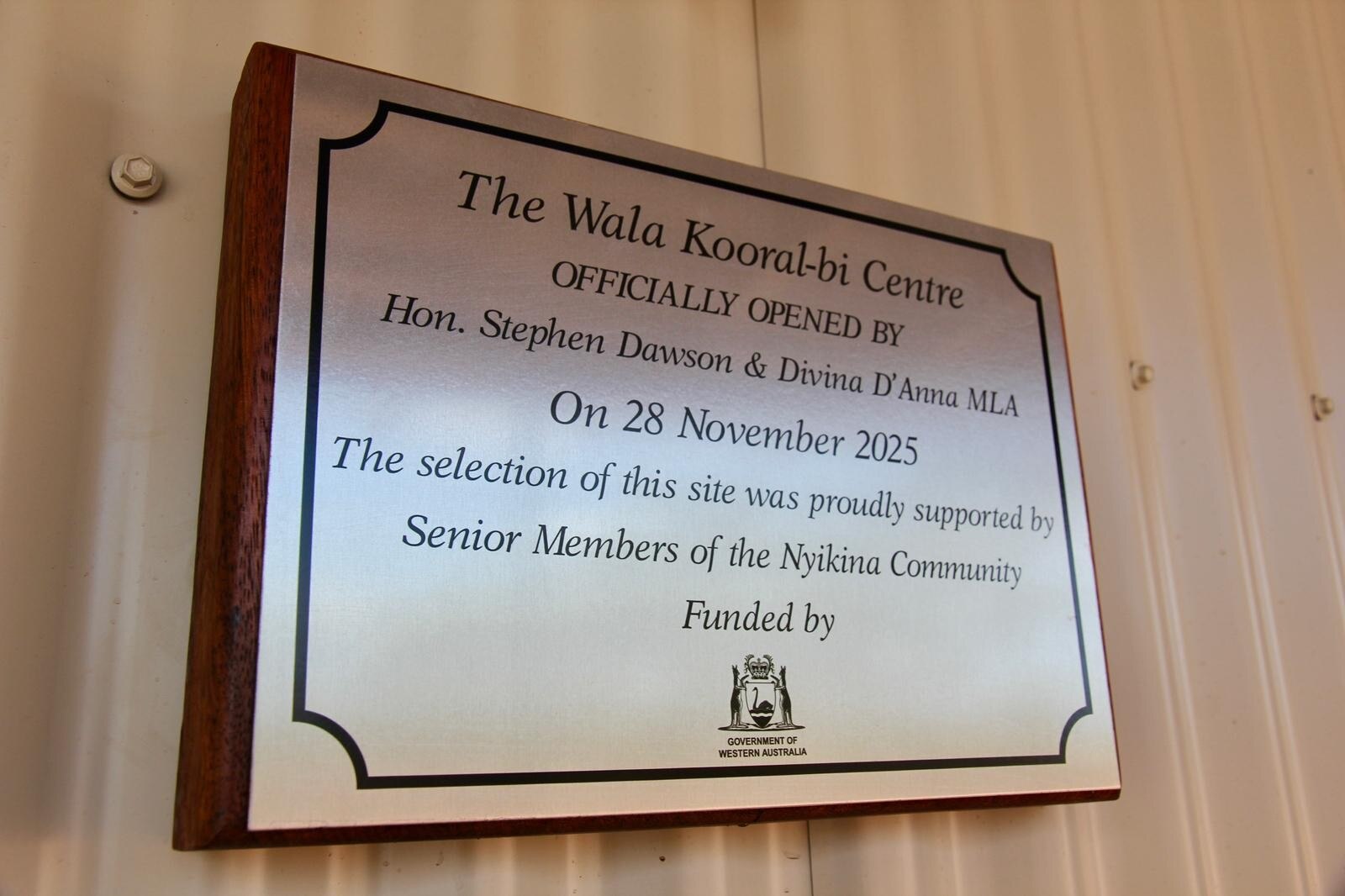 Placa conmemorativa adosada a una pared de chapa para conmemorar la apertura de un centro de detención de menores.