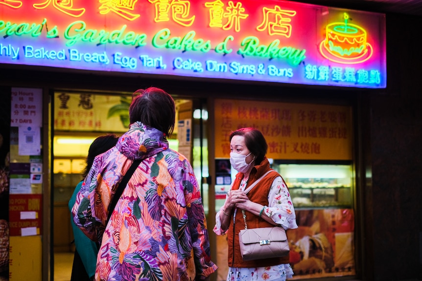 a group of women one wearing a mask standing in front of a shop